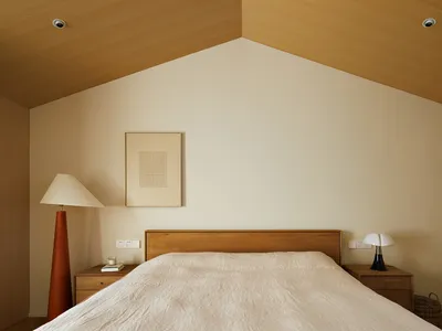 A minimalist bedroom with a wooden headboard, cotton blanket, and white walls.
