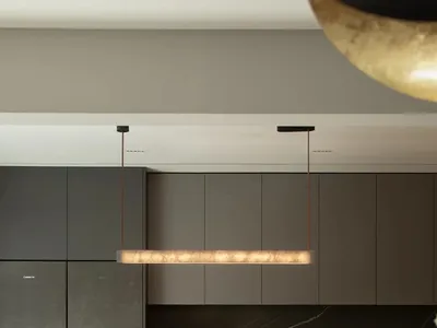 A modern kitchen with marble countertops and cabinets, featuring a dining table and chairs.