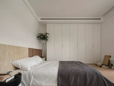 Minimalist bedroom with neutral materials and a large wardrobe.