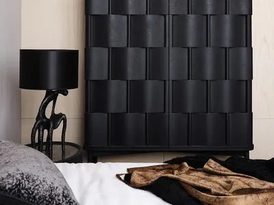 A modern black wood bedroom with furniture, a lamp, and decorative elements.