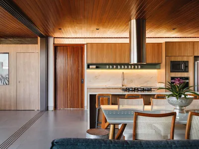 A modern kitchen with wooden cabinets and a glass table.