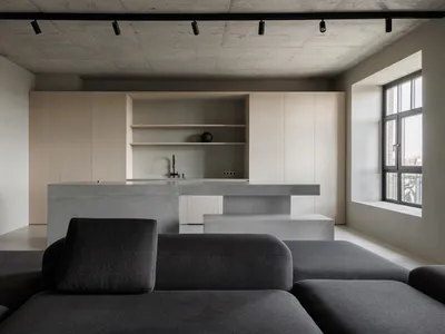 Contemporary living room featuring grey sofas, a concrete kitchen island, and wooden cabinets.
