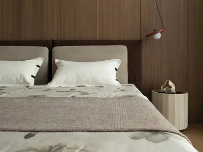 Minimalist bedroom featuring wooden panels and fabric bedding.
