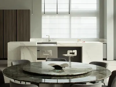 Modern kitchen interior with marble island, white walls, and large pendant lights.