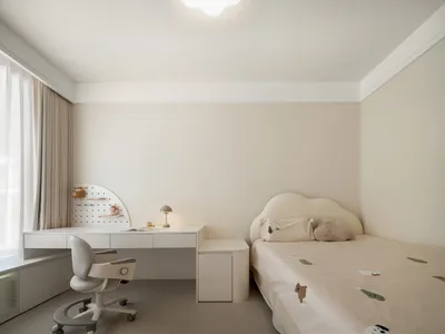 A minimalist bedroom featuring neutral colors and a child's bed with soft textures.