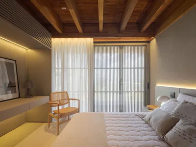 Modern minimalist bedroom featuring a wooden ceiling and soft textiles.