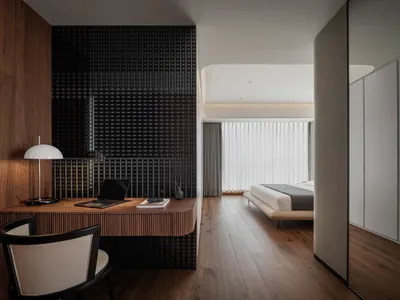 A modern minimalist bedroom with a wooden desk, chair, and floor, featuring a bed with a minimalist design.