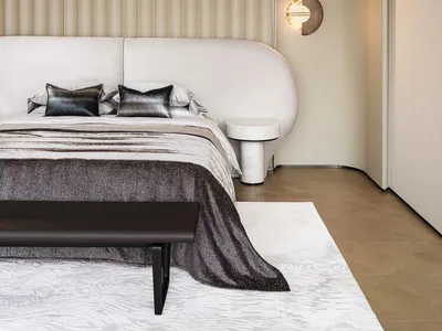 Minimalist bedroom featuring a bed with a cream and taupe striped velvet headboard and matching cover, complemented by a grey