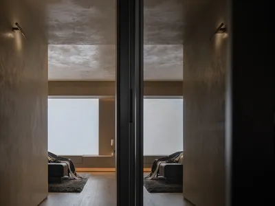 A minimalist bedroom with wooden flooring and furniture.