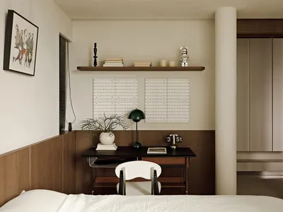 A minimalist bedroom featuring a white bed, wooden desk, and white chair.