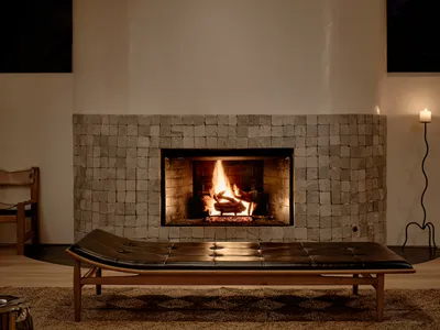 Minimalist living room with a stone fireplace, wood bench, and candle.