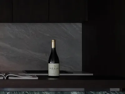現代廚房配備大理石檯面與深色櫥櫃，擺放一瓶Moula Chardonnay白葡萄酒。