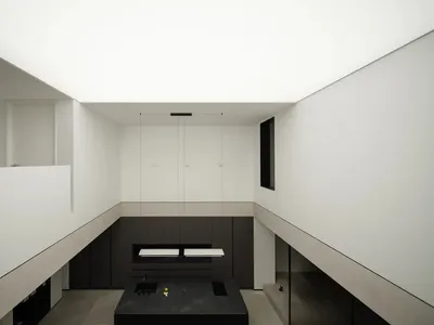 Modern minimalist kitchen with concrete elements, featuring sleek black appliances and a central island with a dark counterto