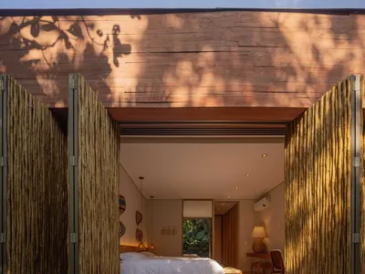 A well-lit bedroom with a wooden floor and a bed, featuring minimalist design and modern furniture.