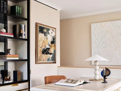 A modern home office featuring a white desk, abstract art, and leather chair.