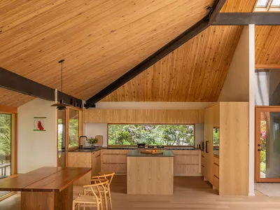 Contemporary residential kitchen featuring wooden cabinets, open floor plan, and large windows.