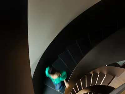 A person climbing a modern, curved staircase made of metal.