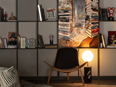 An industrial-style living room with a wooden armchair, bookshelf, and reading nook