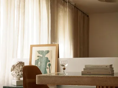 A modern home office with a concrete desk, marble bench, and glass elements.