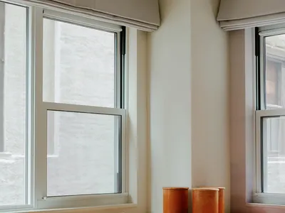 A minimalist industrial home office featuring a wooden desk with a leatherbound notebook, orange containers, and a white chai