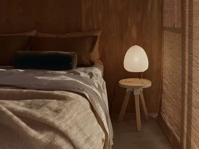 Bedroom features wooden walls and a wooden bedside table with a light lamp.