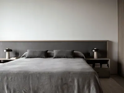 A minimalist bedroom with a gray fabric bedspread and matching pillows.