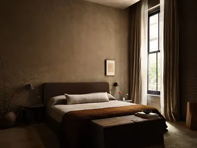 Modern bedroom with minimalist decor and fabric textiles, featuring a bed with a beige pillow and a rustic trunk at the foot