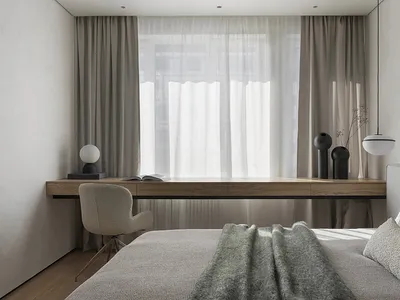 Modern bedroom featuring fabric bedding, a wooden desk, and glass vases.