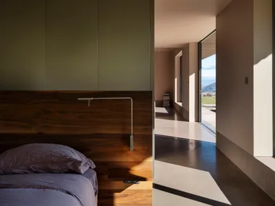A modern bedroom with a brown concrete floor and minimalist design.