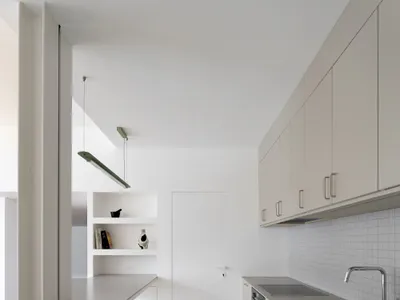 Modern minimalist kitchen with white walls and concrete countertops.