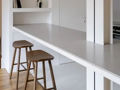 A modern minimalist kitchen with a concrete countertop and pendant light fixture.