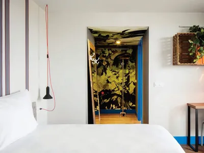 A minimalist bedroom with white walls, a white bed, and a modern design.