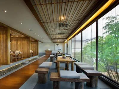 Bamboo restaurant interior with wooden flooring and seating, stone pathway, and large windows.