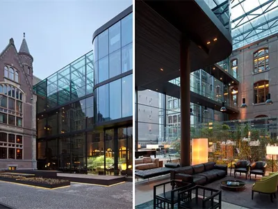 Modern hotel lounge with glass exterior and brick courtyard, featuring contemporary design elements and natural light.