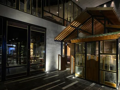 A modern restaurant exterior with wooden accents, glass panes, and concrete walls.