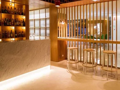 A modern, industrial-style restaurant bar with wooden stools and a wooden divider.