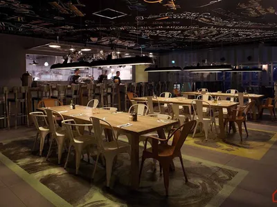 Industrial-themed restaurant with wooden tables and contemporary light fixtures.