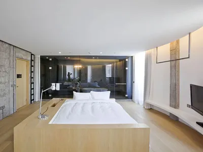 Modern minimalistic bedroom featuring a wooden floating platform bed, white bedding, and minimalist decor.