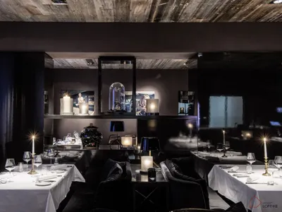 A modern dining room with wooden walls, glass elements, and fabric seating.