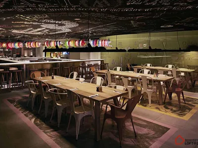 現代工業風餐廳內部，搭配木質家具、黑板天花板與彩色燈籠。
