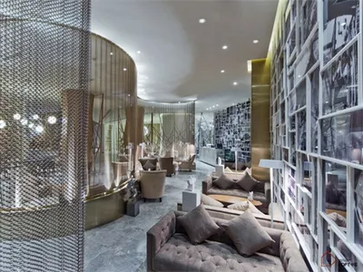Modern hotel lounge with metal chain curtains, glass tables, and plush seating.