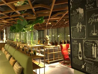 Modern restaurant interior with green seating, wooden accents, and chalkboard wall.
