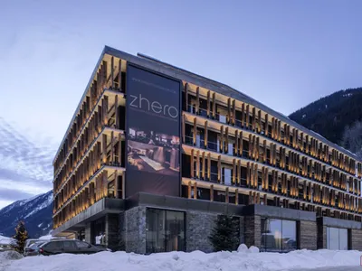 Modern hotel exterior featuring wood, stone, and glass.