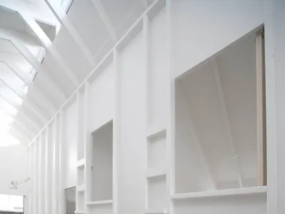 A minimalist bedroom featuring concrete walls and floors, with built-in bunk beds and shelves.