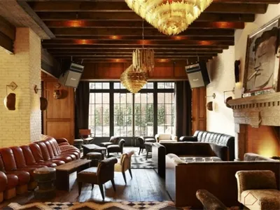 A cozy, industrial-themed hotel lounge featuring brick walls, wooden accents, leather furniture, and metallic chandeliers.