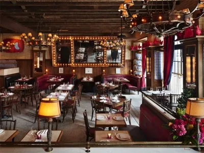 An industrial-themed restaurant interior featuring wooden tables, leather benches, and fabric upholstered chairs.