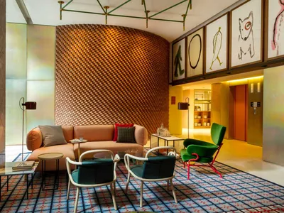 Modern hotel lobby with a textured wooden wall, contemporary furniture, and colorful artwork.