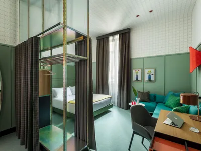A modern hotel room featuring green paneling, curtains, and wooden furniture.