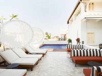 Modern hotel terrace with wooden lounge chairs, glass walls, and a cement patio