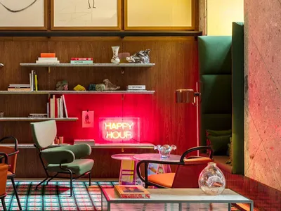 現代餐廳室內，展示木質牆面與層架、皮革座椅，以及寫有「Happy Hour」的霓虹燈招牌。